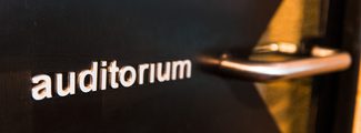 A black door with the word auditorium written on it in white letters