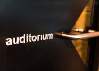 A black door with the word auditorium written on it in white letters