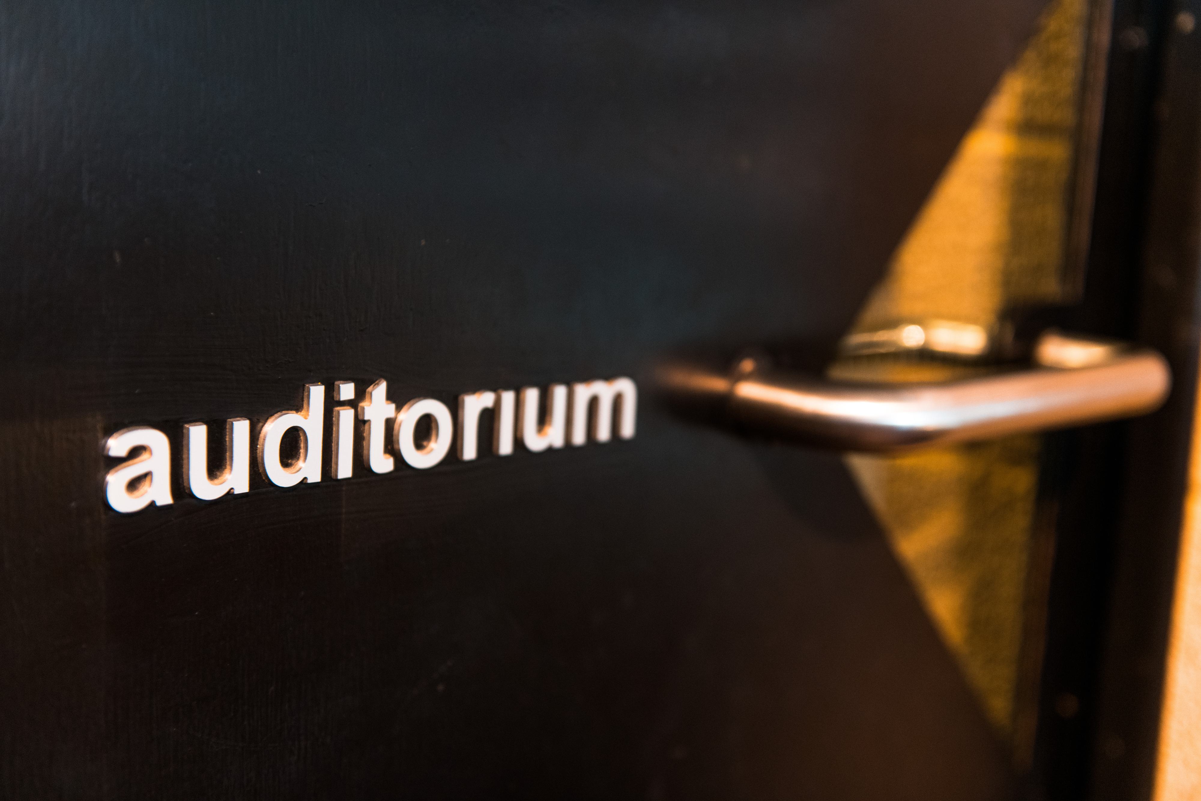 A black door with the word auditorium written on it in white letters