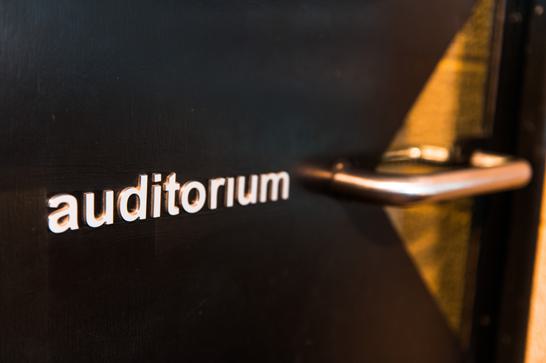A black door with the word auditorium written on it in white letters