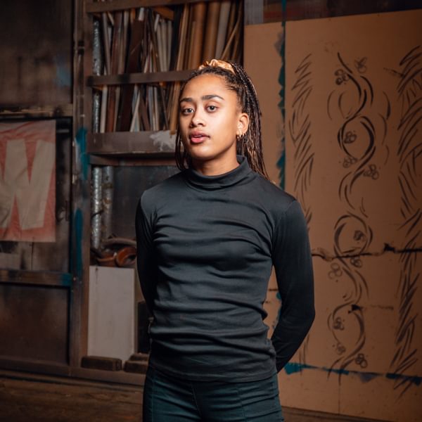 Kassichana Okene Jameson, a woman wearing all black. looks seriously at camera