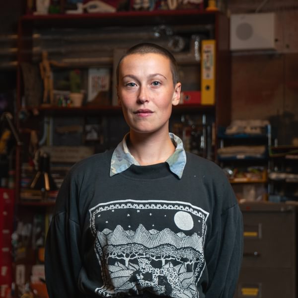 Molly Danter, a person with cropped dark hair wearing a grey jumper looks seriously at camera