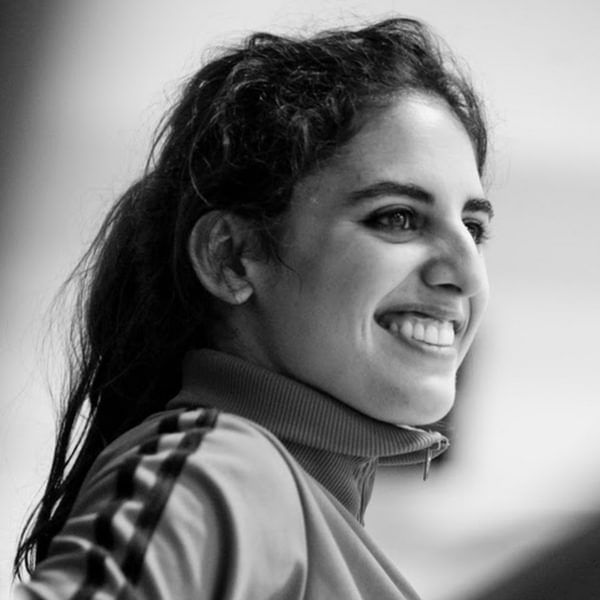 Roser López Espinosa, a woman with long black hair tied up in a ponytail smiles off-camera