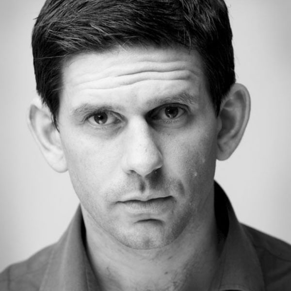 Headshot of Andy Clark, a black and white image of a dark haired man staring seriously into the camera