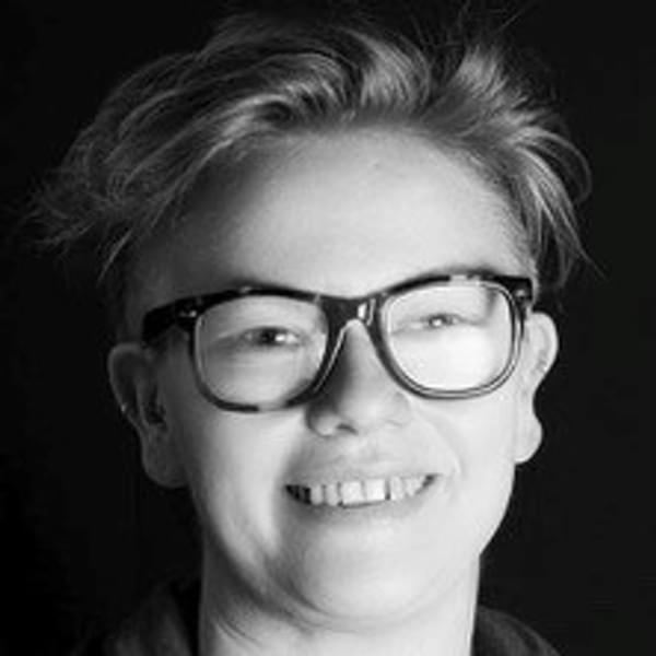 Headshot of Emma Jones, a person wearing glasses with short blonde hair smiling in black and white