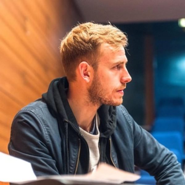 Headshot of Finn Anderson, a blonde man with a beard wearing a blue hoodie and white tshirt