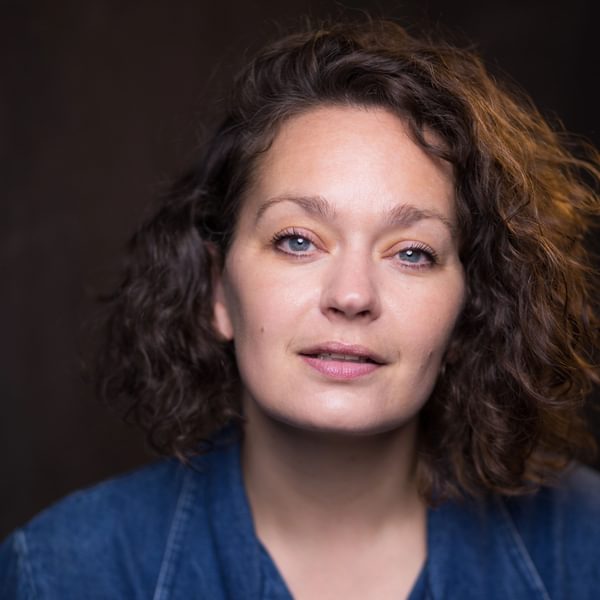 Headshot of Vicki Manderson, a woman with brown curly hair wearing a blue top